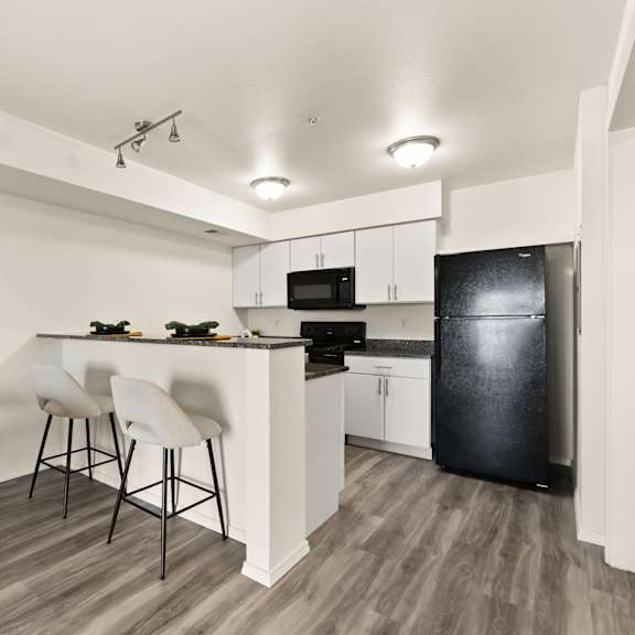 a kitchen with a black fridge and white cabinets.