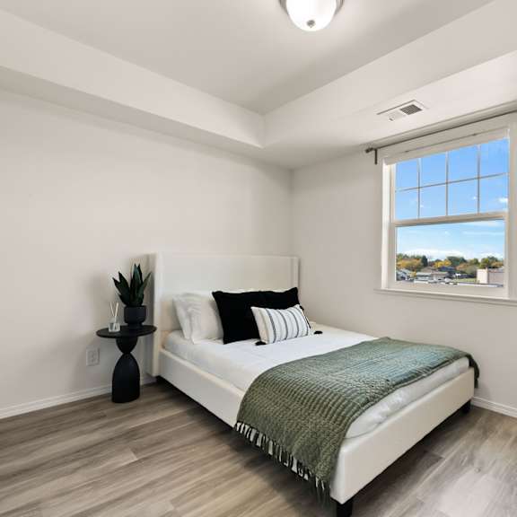 a bedroom with a bed, a chair, and a window with a view of the sky.