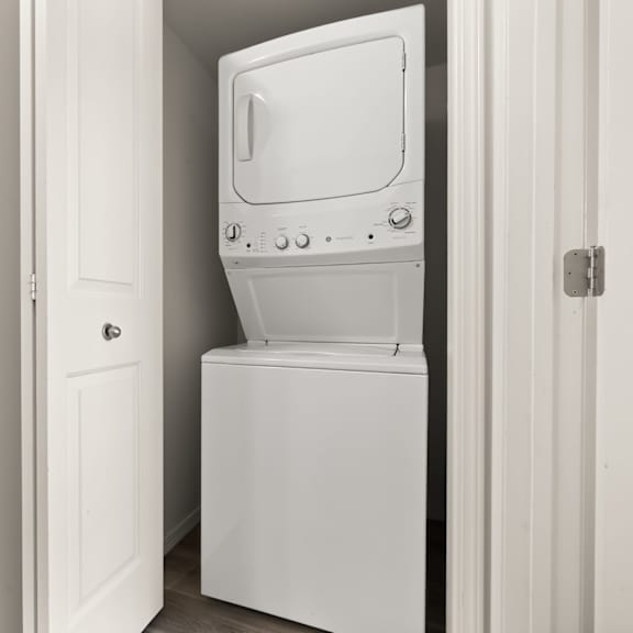 a white washing machine is in a small white door.