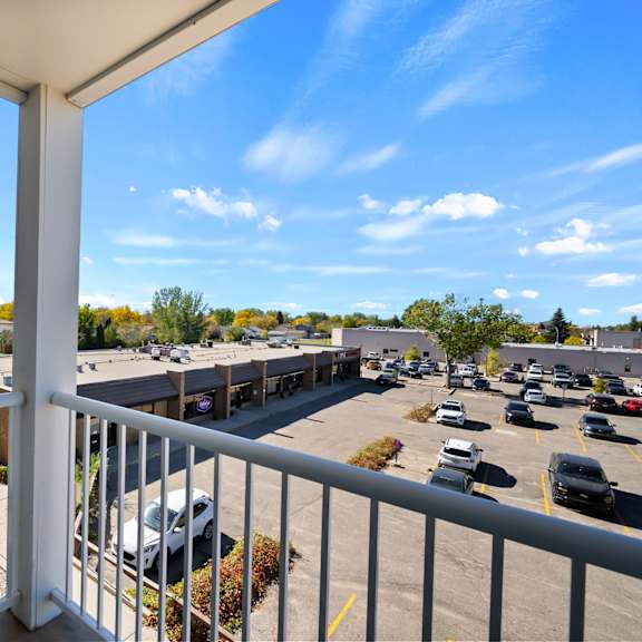 a balcony overlooks a parking lot and buildings.