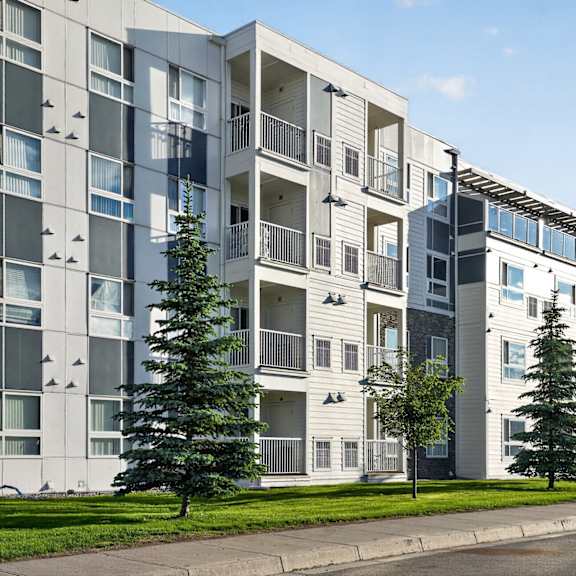 a modern apartment building with balconies and trees in front.