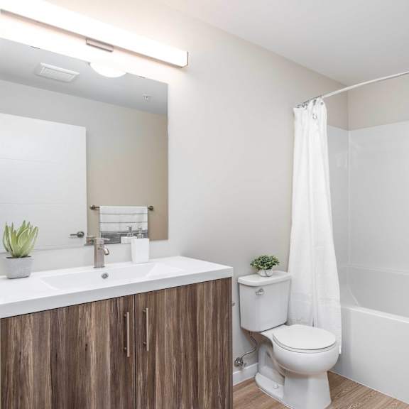 a white bathroom with a toilet, sink, and shower. at g17 apartments at tamarack, edmonton