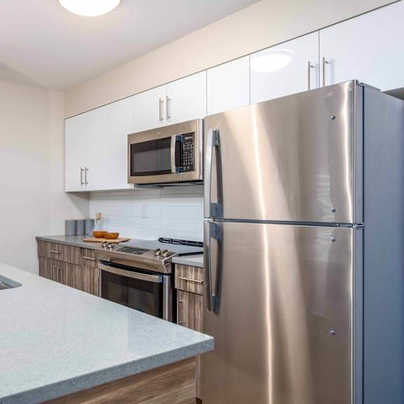 a kitchen with a stainless steel refrigerator, microwave, and sink. at g17 apartments at tamarack, edmonton, alberta