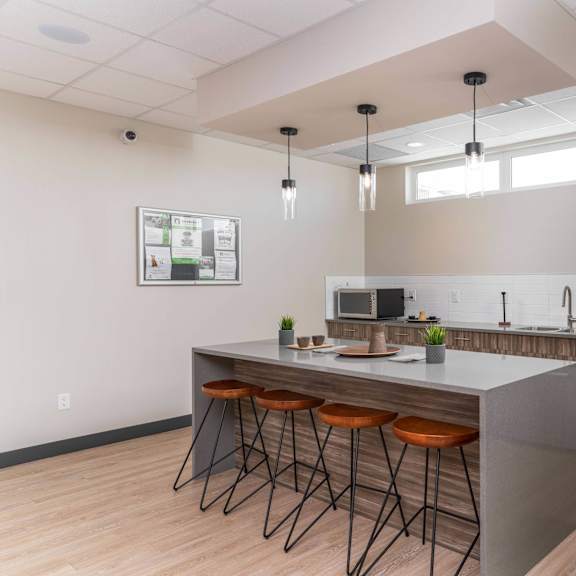 a modern kitchen with a bar area and stools. at g17 apartments at tamarack, edmonton, ab