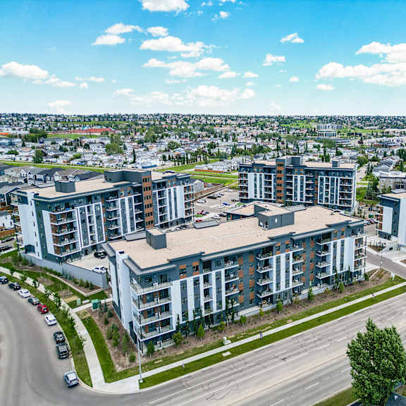 a large apartment complex is situated on a street corner with a road and cars in the foreground.