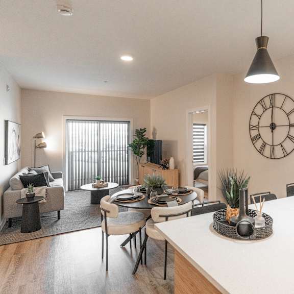 a modern kitchen with a dining table and chairs, a clock on the wall, and pendant lights hanging above the island.at vista apartments at edgemont, edmonton, t6m 1j4