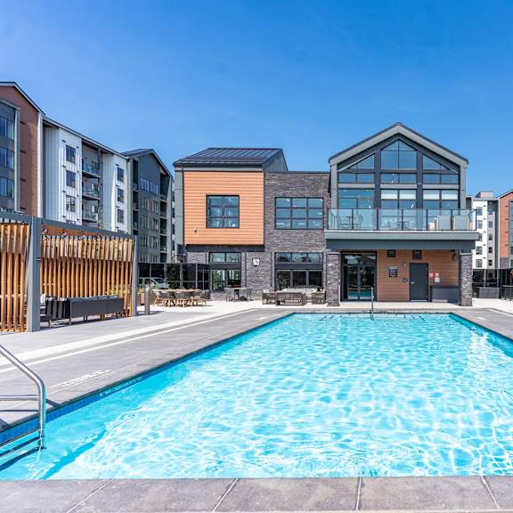 a large swimming pool in front of a building with a glass facade.