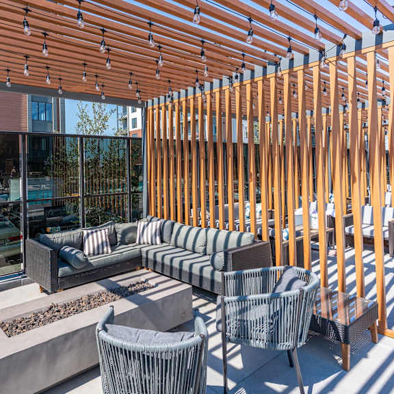 a wooden patio with a couch, chairs, and a fire pit.