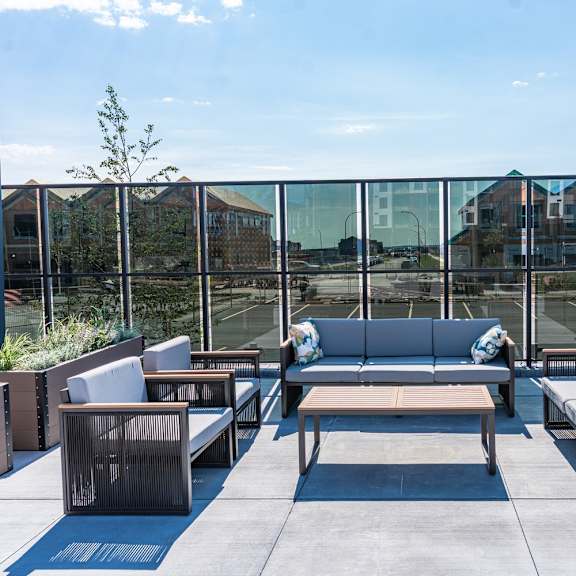 a patio with a glass wall and furniture.