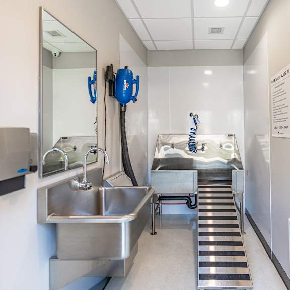 a clean, well-lit hospital room with a sink, mirror, and medical equipment.