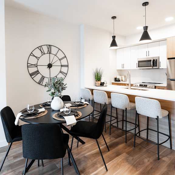 a modern kitchen with a dining table set for four.at podium apartments, calgary, ab
