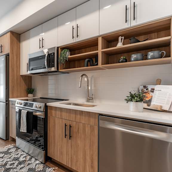 a modern kitchen with wooden cabinets and stainless steel appliances.at podium apartments, calgary, ab