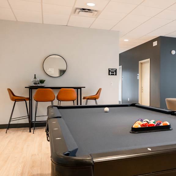 a pool table is in the middle of a room with a tv and a couch.