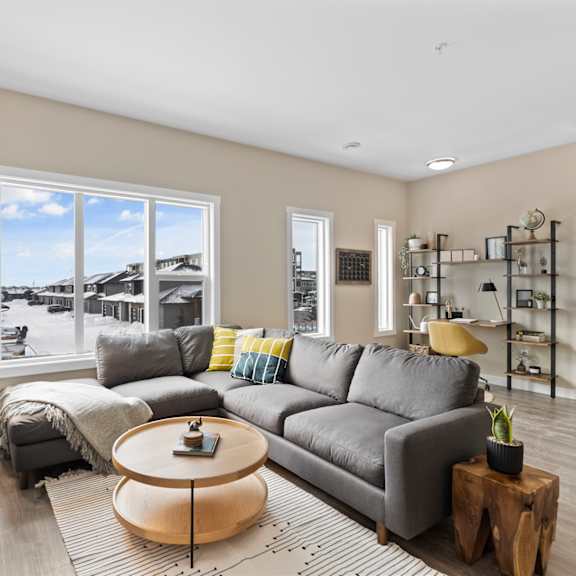 a modern living room with a grey sofa and a large window.