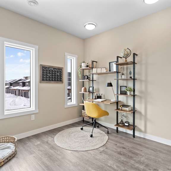 a room with a yellow chair and a desk with a shelf.