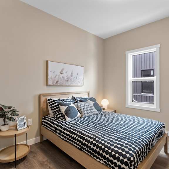 a bedroom with a bed, nightstand, and a painting on the wall.
