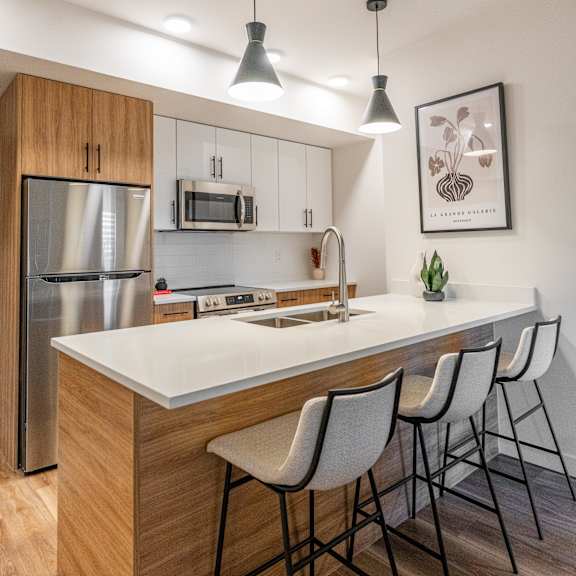 a kitchen with a white countertop and wooden cabinets. at the artisan at rangeview, calgary, alberta