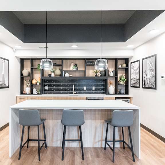 a modern kitchen with a bar area and three grey bar stools.