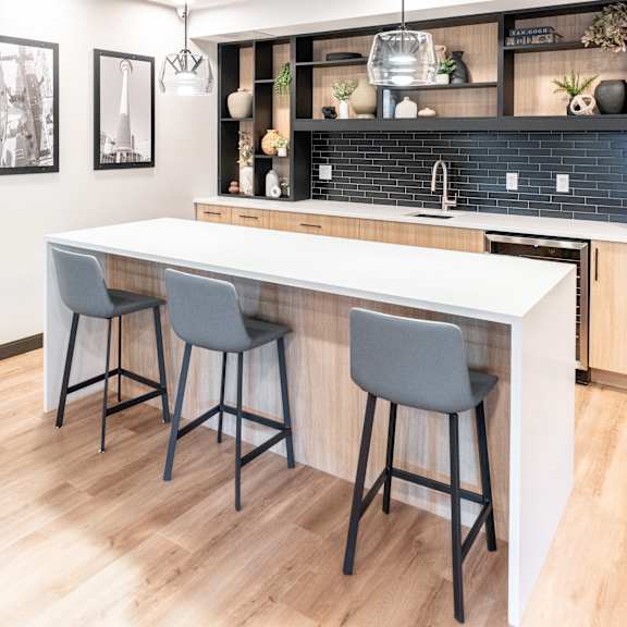 a kitchen with a white counter and two grey bar stools.