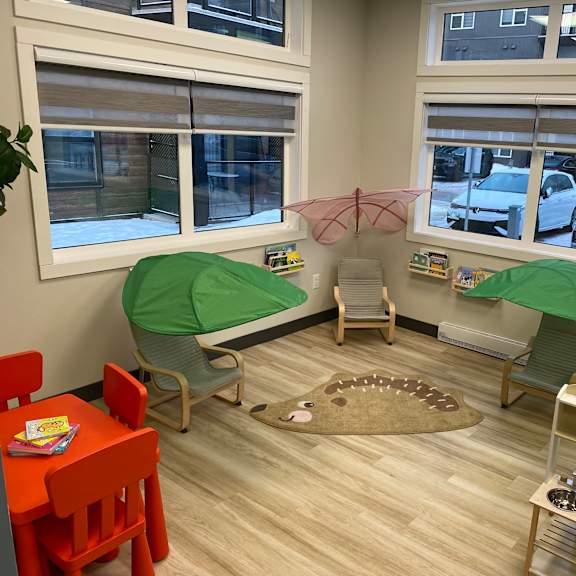 a room with a table, chairs, and a playpen.