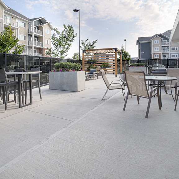 a patio with chairs and tables is surrounded by buildings.