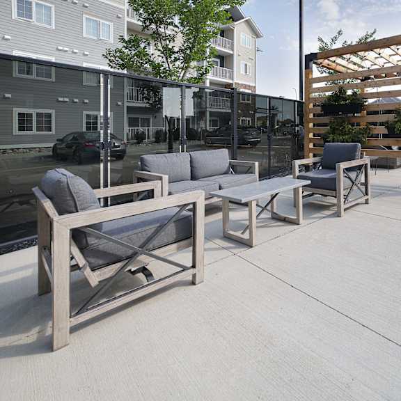 a patio with a wooden pergola and grey couches.