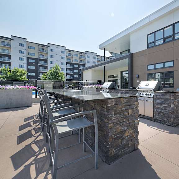 a modern outdoor seating area with a stone barrier and metal chairs.