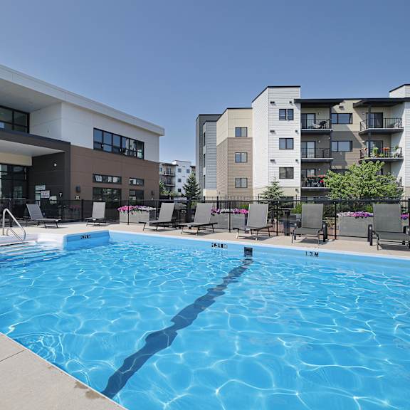 a large swimming pool in front of a building with apartment complexes in the background.