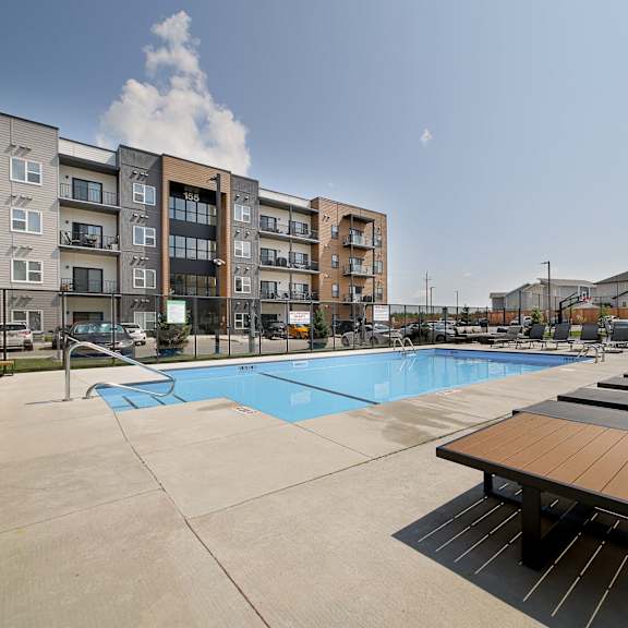 a swimming pool surrounded by sun loungers and apartment buildings.