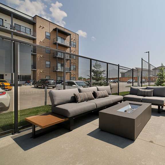 a modern outdoor seating area with a concrete floor and a black fence.