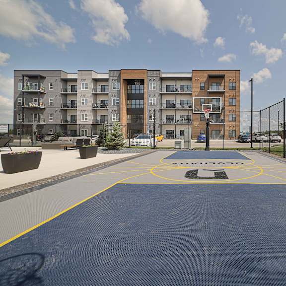 a basketball court in front of a multi-story apartment building.