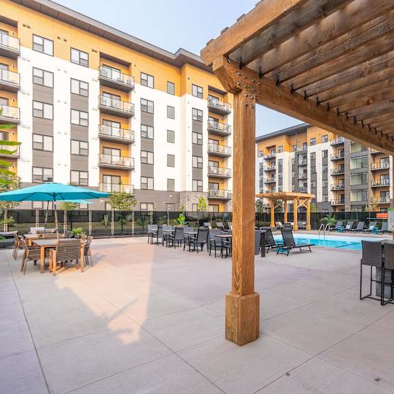 a wooden pergola is over a patio with a table and chairs.