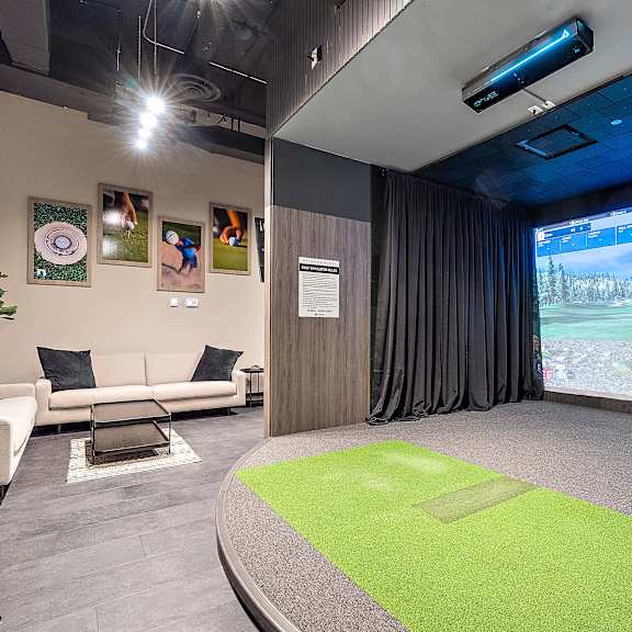 a room with a projector screen and couches and a green rug
