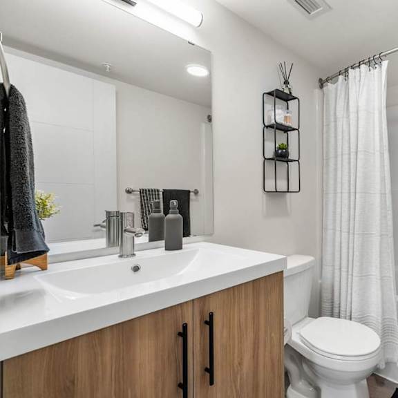 modern bathroom with wood vanity and white fixtures at mac and mullen apartments, edmonton, ab t6r 0s7