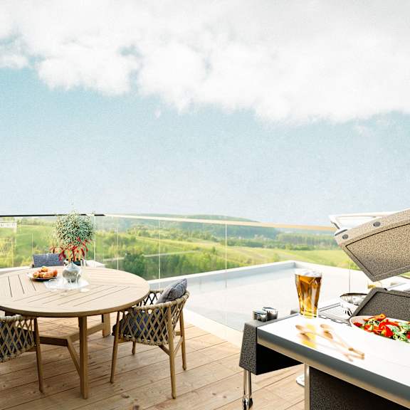 a table with chairs and a grill on a balcony overlooking a field.