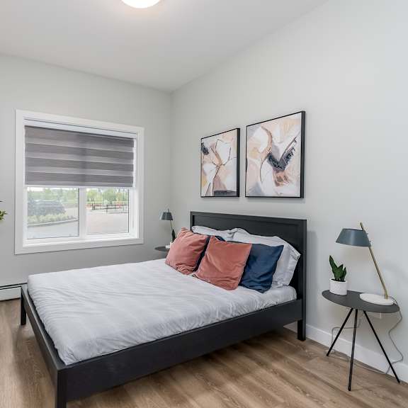 a bedroom with a bed, two lamps, and two pictures on the wall.