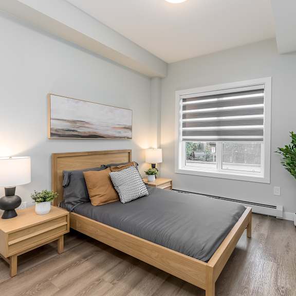 a bedroom with a bed, nightstand, and a plant.