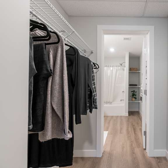 a hallway with a white door and a rack of clothes.