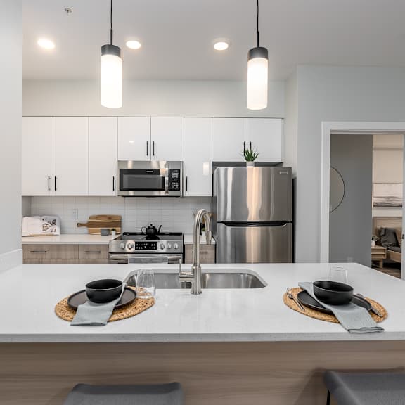 a modern kitchen with a white countertop and stainless steel appliances.