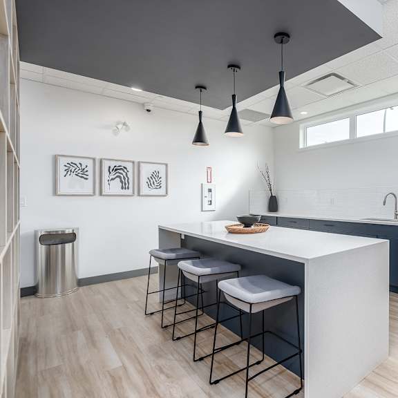a modern kitchen with a white island and stools.