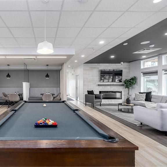 a pool table is in the middle of a room with a couch and a fireplace.