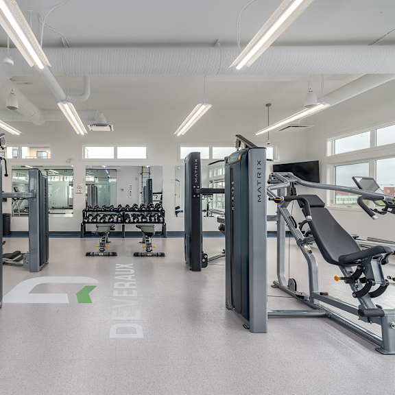 a gym with a variety of equipment including treadmills, weights, and exercise machines.