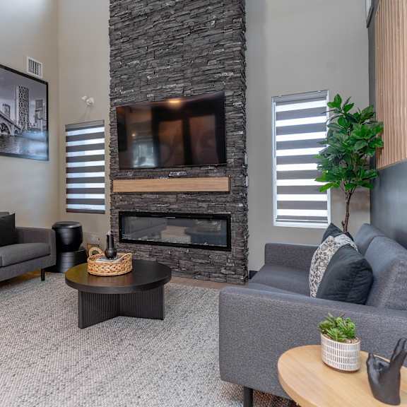 a living room with a grey couch, a coffee table, and a fireplace. at vibe apartments at arbour lake, alberta