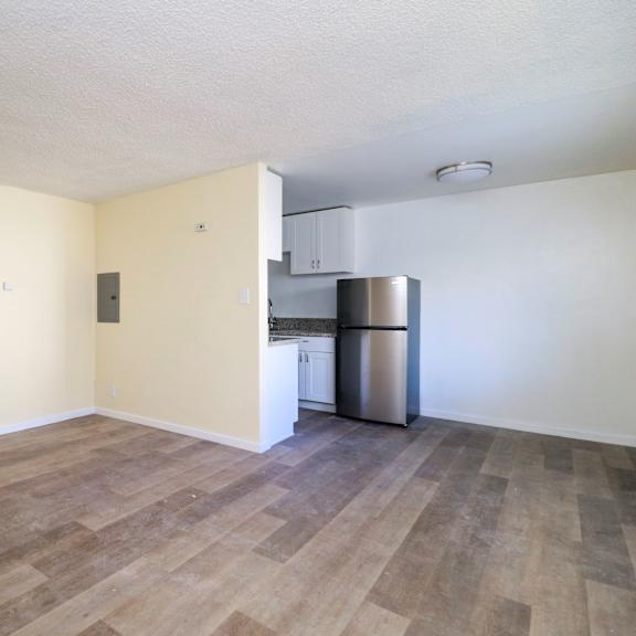 a room with wooden flooring and a stainless steel refrigerator.