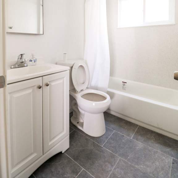a white toilet is in a bathroom with a white cabinet and a window.