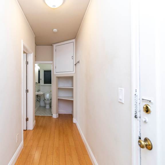 a hallway with a white door and a white wall.