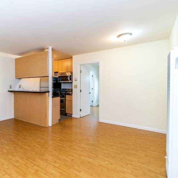 a kitchen area with wooden floors and cabinets.