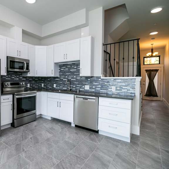 a modern kitchen with a stainless steel refrigerator and white cabinets.