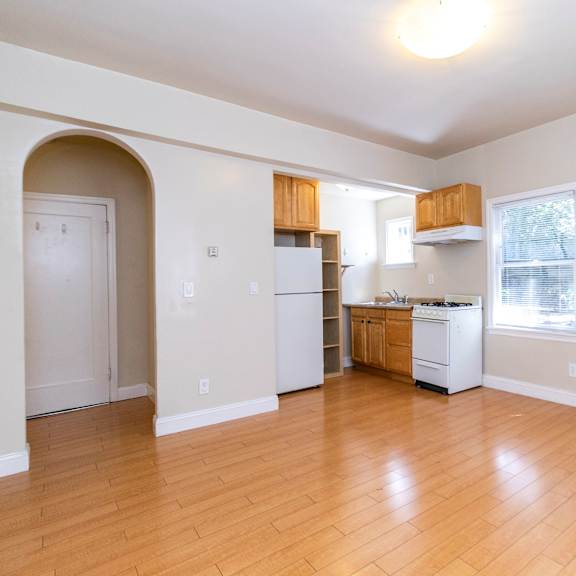 a kitchen with white appliances and wooden floors.