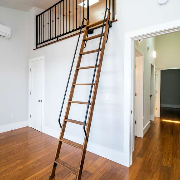 a wooden staircase with a black railing leads up to a white door.